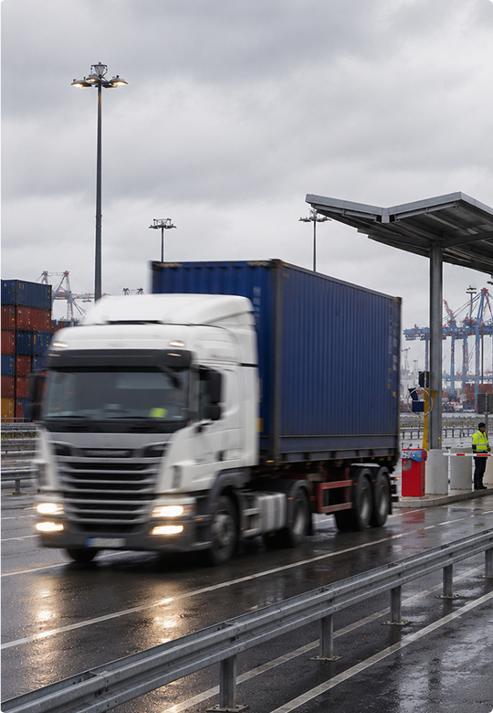 Truck carrying a shipping container through a port customs checkpoint
